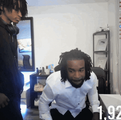 A Man In A White Shirt Is Sitting In Front Of A Table With The Number 192 Visible GIF