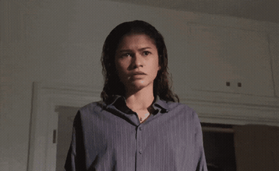 A Man In A White Shirt Is Sitting On A Bed Looking At A Tablet GIF
