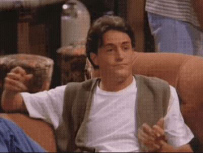 A Man In A White Shirt Is Sitting On A Couch With His Arms Outstretched GIF