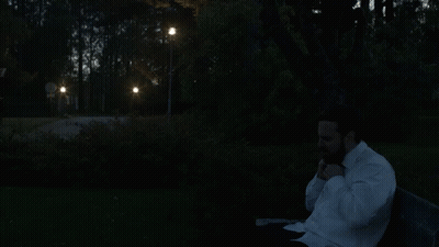 A Man In A White Shirt Is Sitting On A Park Bench GIF