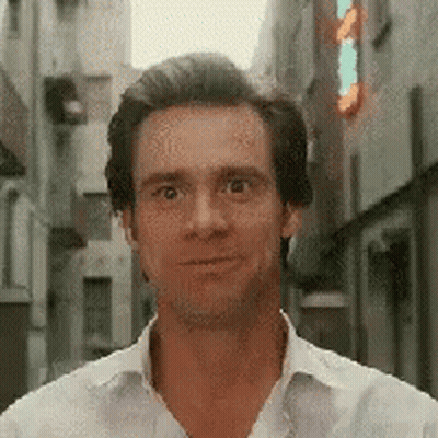 A Man In A White Shirt Is Smiling And Looking At The Camera . GIF