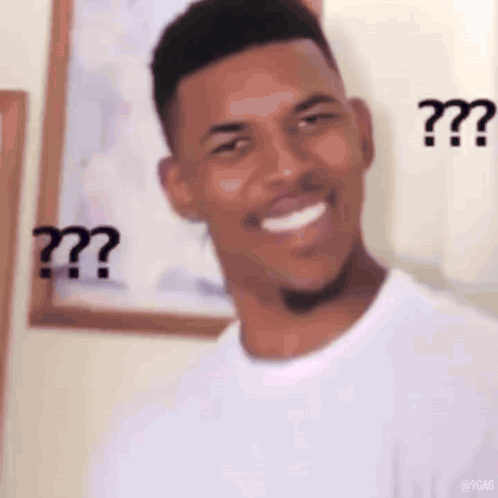 A Man In A White Shirt Is Smiling And Making A Funny Face With Two Question Marks On His Face . GIF