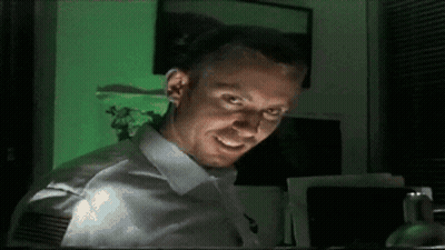 A Man In A White Shirt Is Smiling In Front Of A Green Screen GIF