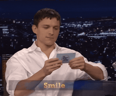 A Man In A White Shirt Is Smiling While Holding A Piece Of Paper GIF