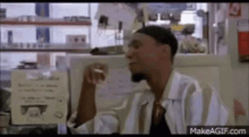 A Man In A White Shirt Is Smoking A Cigarette In A Diner . GIF