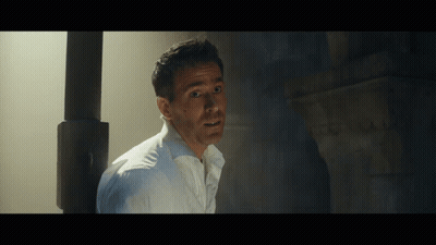 A Man In A White Shirt Is Standing In A Dark Room With His Mouth Open GIF