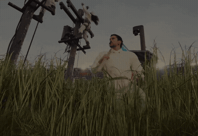 A Man In A White Shirt Is Standing In A Field With A Stadium In The Background GIF