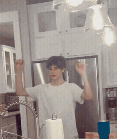 A Man In A White Shirt Is Standing In A Kitchen Near A Paper Towel Dispenser GIF