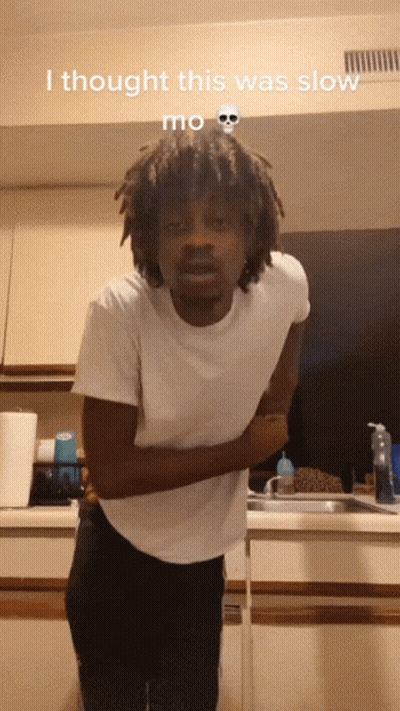 A Man In A White Shirt Is Standing In A Kitchen With The Words I Thought This Was Slow Mo On The Bottom GIF