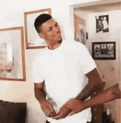 A Man In A White Shirt Is Standing In A Living Room Holding A Woman 'S Hand . GIF