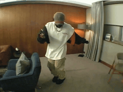 A Man In A White Shirt Is Standing In A Room GIF