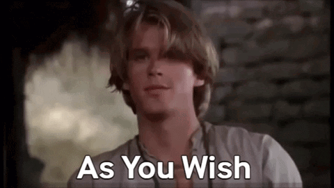 A Man In A White Shirt Is Standing In Front Of A Brick Wall And Says `` As You Wish '' . GIF