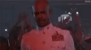A Man In A White Shirt Is Standing In Front Of A Crowd Of People . GIF