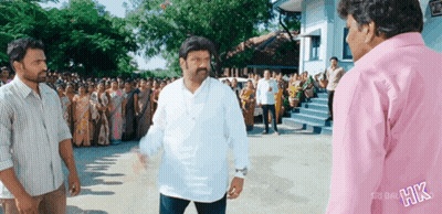 A Man In A White Shirt Is Standing In Front Of A Crowd Of People With The Word Hk On The Back Of His Shirt GIF