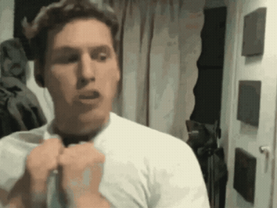 A Man In A White Shirt Is Standing In Front Of A Door GIF