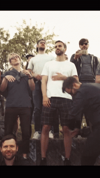 A Man In A White Shirt Is Standing In Front Of A Group Of People GIF