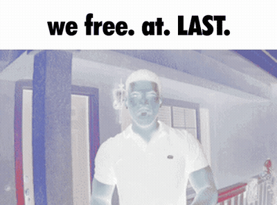 A Man In A White Shirt Is Standing In Front Of A House With The Words " We Free At Last " Above Him GIF