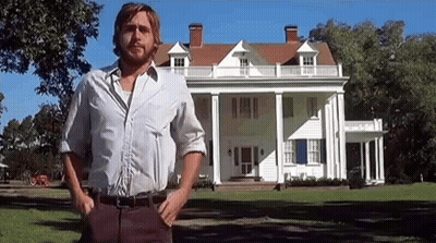 A Man In A White Shirt Is Standing In Front Of A Large White House . GIF