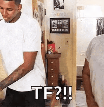 A Man In A White Shirt Is Standing In Front Of A Mirror In A Room And Says `` Tf ? '' . GIF