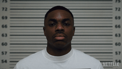 A Man In A White Shirt Is Standing In Front Of A Netflix Wall GIF