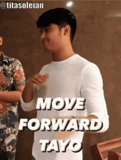 A Man In A White Shirt Is Standing In Front Of A Sign That Says `` Move Forward Tayo '' . GIF