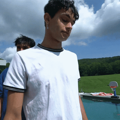 A Man In A White Shirt Is Standing In Front Of A Swimming Pool GIF