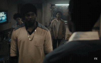 A Man In A White Shirt Is Standing In Front Of A Tv Screen That Says Fx GIF