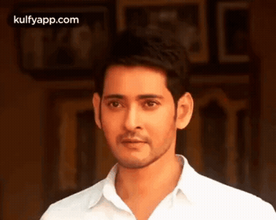 A Man In A White Shirt Is Standing In Front Of A Wall . GIF