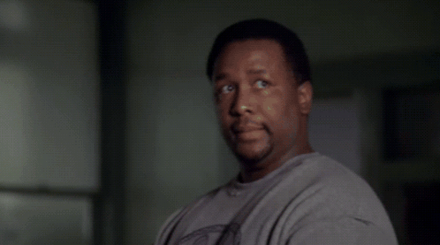 A Man In A White Shirt Is Standing In Front Of A Window GIF