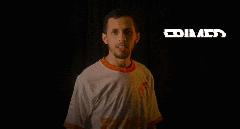A Man In A White Shirt Is Standing In The Dark With The Word Frimed Behind Him GIF