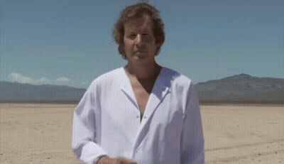 A Man In A White Shirt Is Standing In The Desert GIF