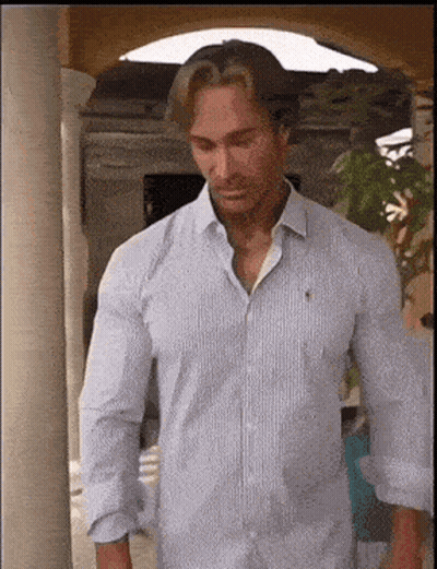 A Man In A White Shirt Is Standing Next To A Pillar . GIF