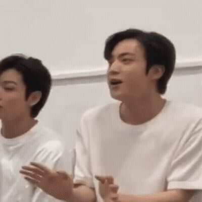 A Man In A White Shirt Is Standing Next To Another Man . GIF
