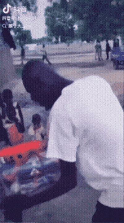 A Man In A White Shirt Is Standing On A Street With A Tiktok Logo On The Bottom Left GIF