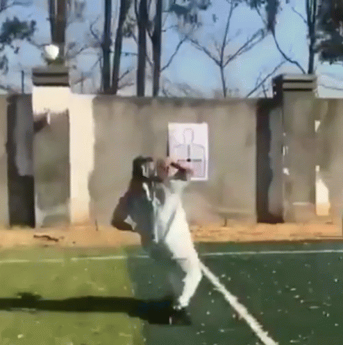 A Man In A White Shirt Is Standing On A Tennis Court With A Target In The Background .. GIF