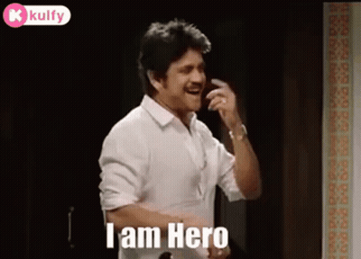 A Man In A White Shirt Is Talking On A Cell Phone While Standing In A Room . GIF