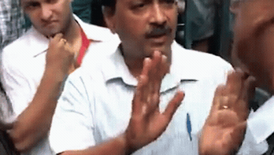 A Man In A White Shirt Is Talking To Another Man In A Crowd With His Hands Outstretched . GIF