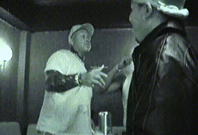 A Man In A White Shirt Is Talking To Another Man GIF
