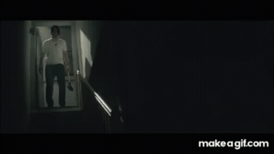 A Man In A White Shirt Is Walking Down A Set Of Stairs With A Knife In His Hand . GIF