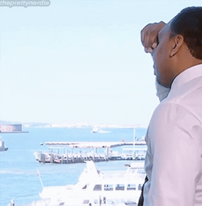 A Man In A White Shirt Looks Out A Window At The Water GIF