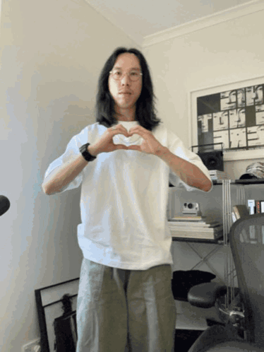 A Man In A White Shirt Making A Heart Shape GIF