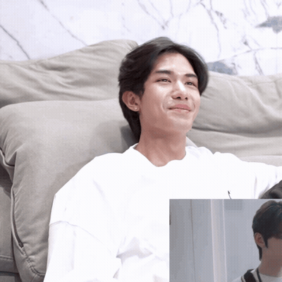 A Man In A White Shirt Sits On A Grey Couch GIF