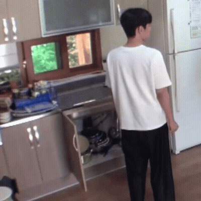 A Man In A White Shirt Stands In A Kitchen GIF