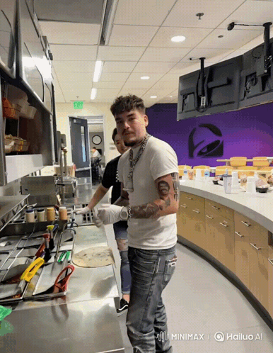A Man In A White Shirt Stands In A Kitchen With A Taco Bell Logo In The Background GIF