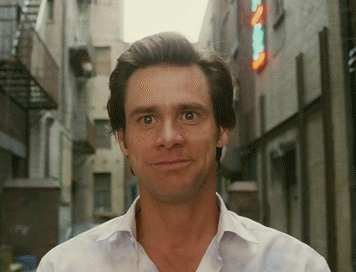 A Man In A White Shirt Stands In A Narrow Alleyway Looking At The Camera GIF