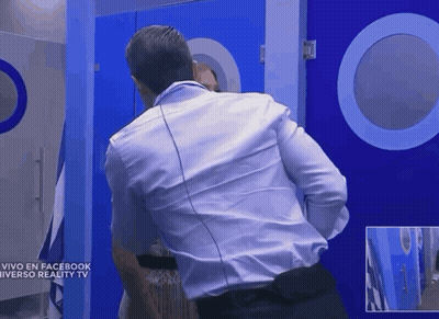 A Man In A White Shirt Stands In Front Of A Blue Door That Says Vivo En Facebook Universo Reality Tv GIF