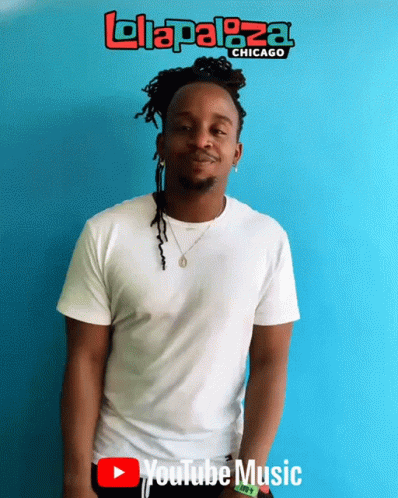 A Man In A White Shirt Stands In Front Of A Blue Wall That Says Lolaplaza Chicago GIF