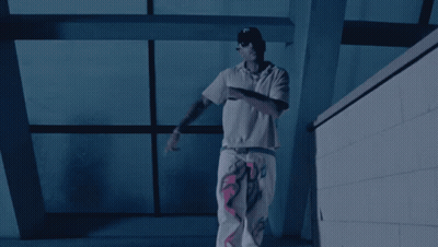 A Man In A White Shirt Stands In Front Of A Window GIF