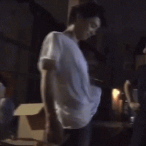 A Man In A White Shirt Stands Next To Another Man In A Hat GIF