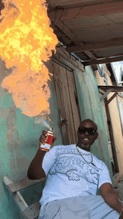 A Man In A White Shirt With A Crocodile On It Is Holding A Can Of Spray Paint GIF